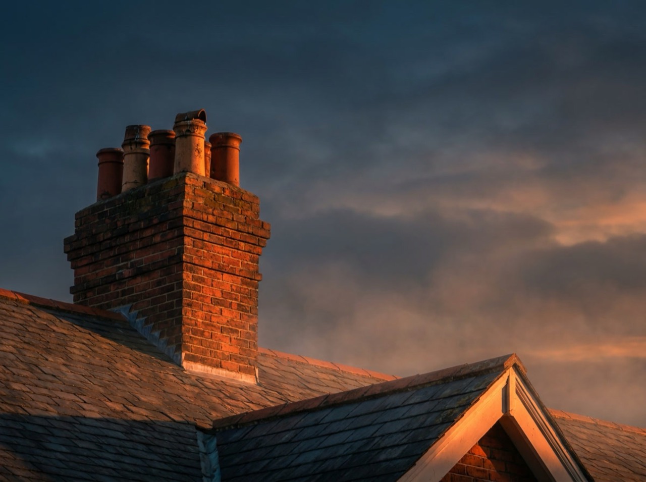 A Boone's Chimney sweep on the roof of a brick home at dusk